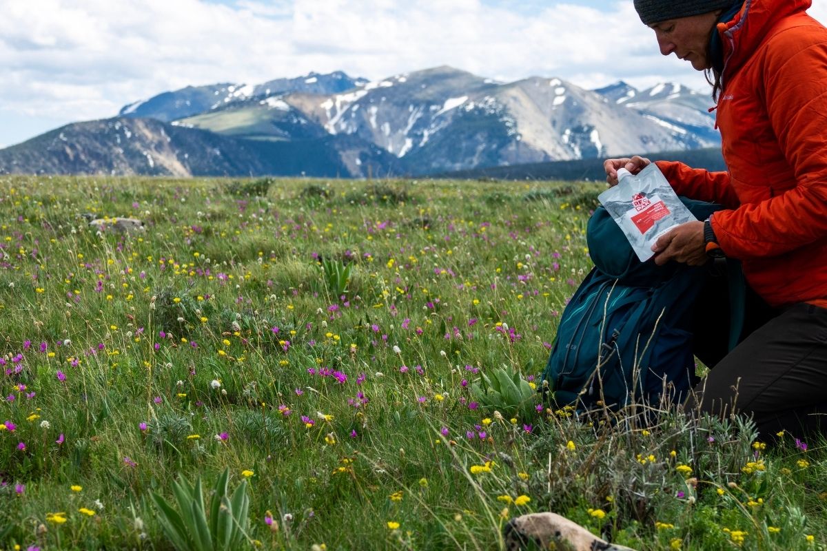 Man in meadows holding Recpak - an Veteran-Owned Ultralight Meal Company