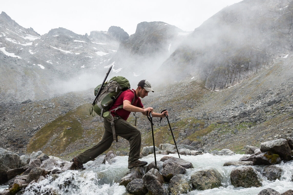 Mountaineer crossing rocks and water, after using Recpak the best backpacking meal