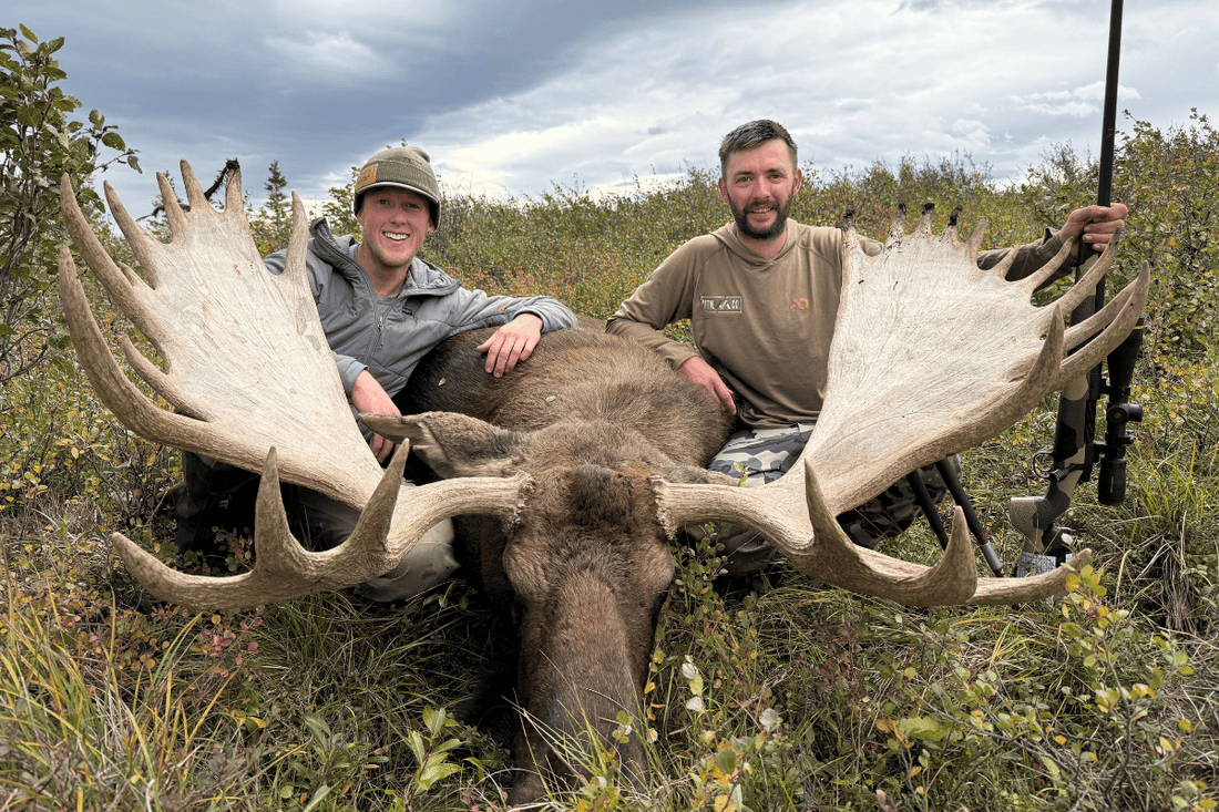 two hunters sitting by a large moose they just took down using RecPak to fuel them. 