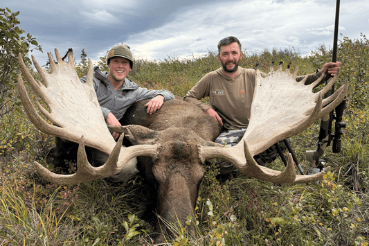 two hunters sitting by a large moose they just took down using RecPak to fuel them. 
