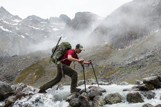 backpacker crossing a river  in the mountains - Master essential backcountry tips